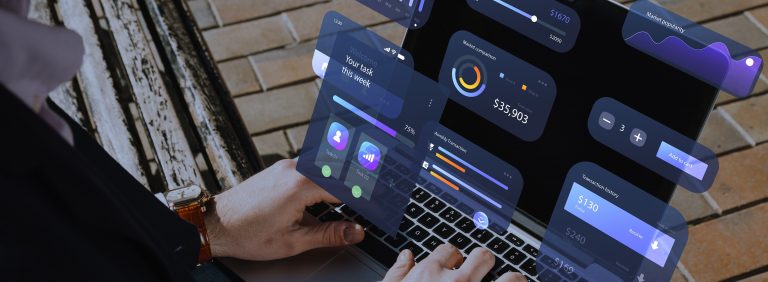 Pessoa usando notebook com tela exibindo gráficos interativos e painéis de dashboard financeiro, com dados de vendas, comparação de mercado e transações mensais, ilustrando interface de BI (Business Intelligence) ou sistema de análise de dados para gestão empresarial.